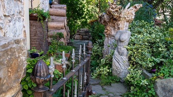 Traumgarten in Saalfeld: Eine nackte Frauenbüste steht in einem Garten inmitten üppiger Pflanzen.