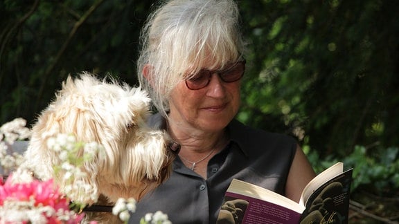 Gartenjournalistin Victorica Summerley liest mit ihrem Hund Rufus ein Buch.  