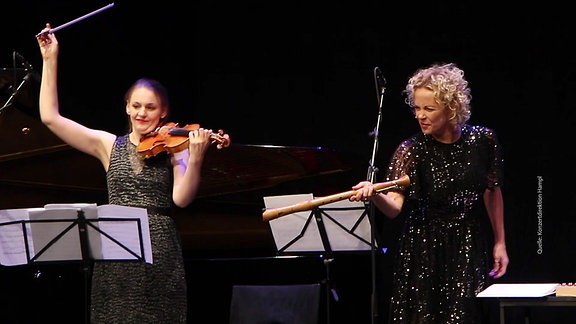 Schauspielerin Katja Riemann steht auf einer Bühne mit einer Altflöte.