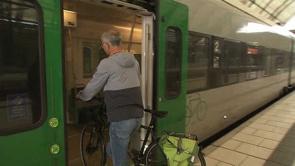 Mann mit Fahrrad besteigt eine S-Bahn