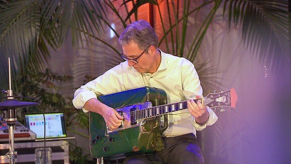 Ein Mann spielt eine Gitarre, deren Körper aus einem Kanister gemacht wurde