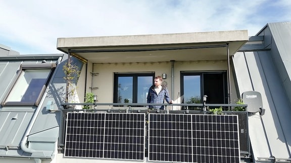 Ein Mann auf dem Balkon mit einer Balkon-Solaranlage