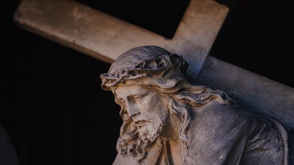 Eine Figur des Jesus Christus mit dem Kreuz an der Fassade eines Hauses