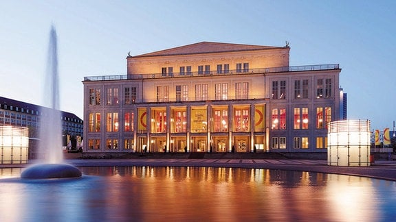 Blick auf das erleuchtete Leipziger Opernhaus in der Dämmerung. 