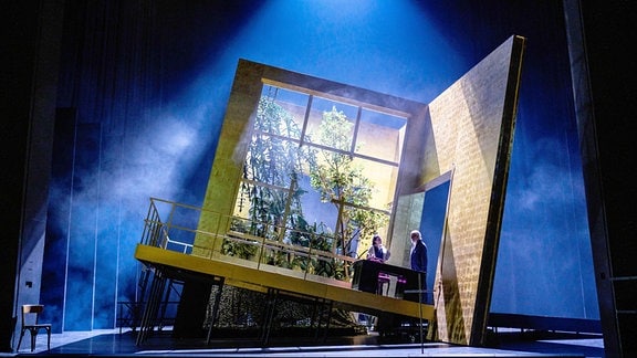 Szene aus der Oper "Missing in Cantu": Auf der Bühne ist eine goldene Kulisse als Zimmer zu sehen, das allerdings total schief steht.