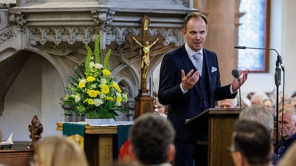 Ein Redner (Michael Maul) spricht am Rednerpult in einer Kirche.