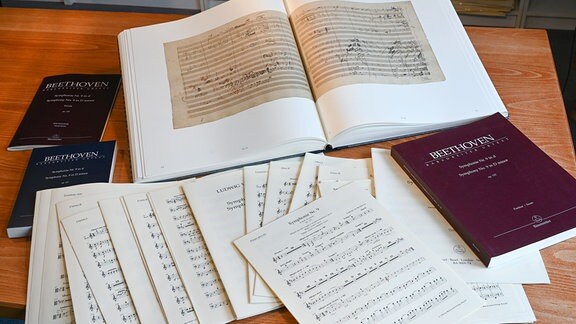 Verschiedene Notenblätter von Beethovens Sinfonie Nr. 9 mit der Faksimile-Ausgabe (oben) liegen im Bärenreiter-Verlag.