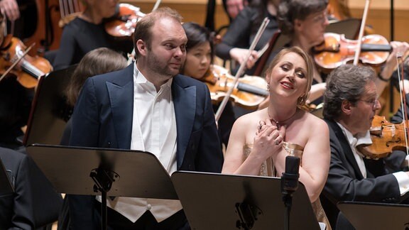 Eine Sängerin und ein Sänger auf der Bühne beim Konzert von "Die drei Pintos" im Rahmen des Mahler-Festivals 2023 in Leipzig. Im Hintergrund spielt das Gewandhausorchester.