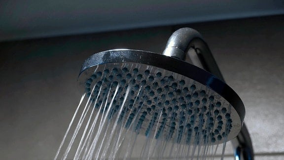 Duschkopf einer Dusche mit fließenden Wasser in einem Badezimmer im Hotel