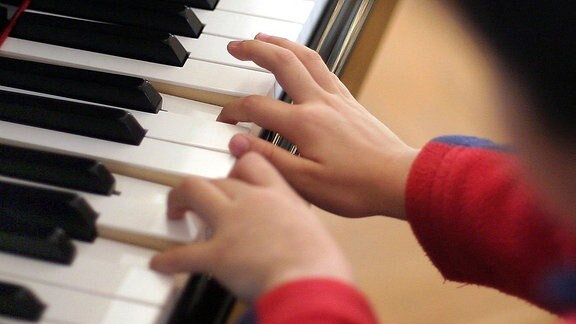 Hände eines Kindes an den Klaviertasten.