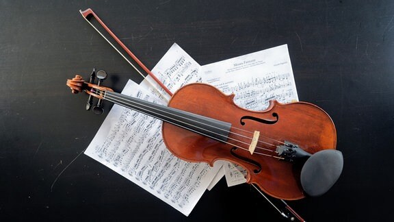 Eine Geige mit Notenblättern liegt auf dem Tisch