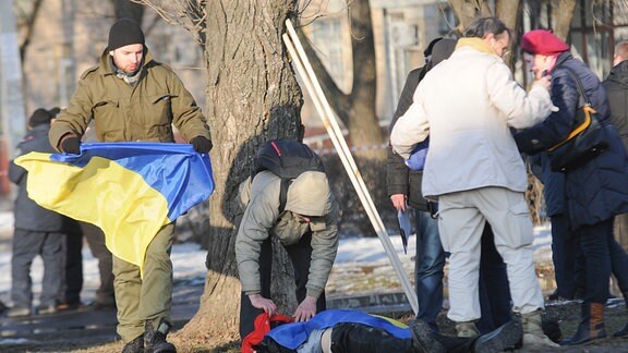 Krieg in der Ukraine: Zivilisten in Charkow. Ein Mann trägt eine ukrainische Flagge.