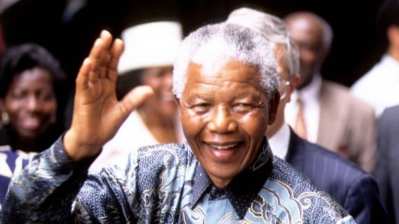 Nelson Mandela hebt die Hand.