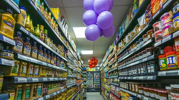 Blick in einen Supermarkt. Im Gang hängen Luftballons.