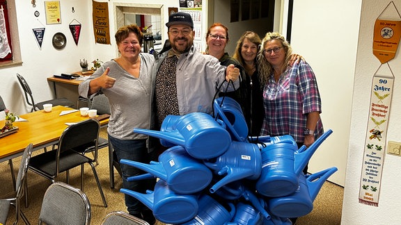 Petra, Lars, Kati, Barbara (Ortsbürgermeisterin von Libbesdorf) und Simone stehen von hellblauen Gießkannen