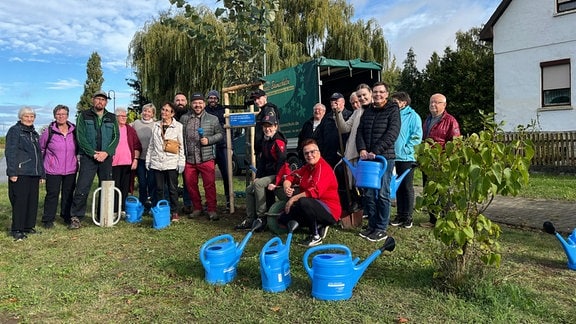 Eine Gruppe Menschen stehen zusammen mit blauen Kießkannen.