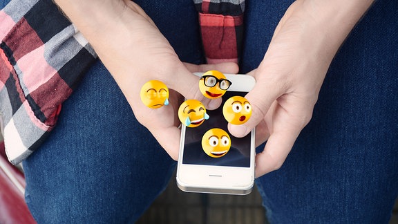 Mann versendet Emojis mit einem Smartphone