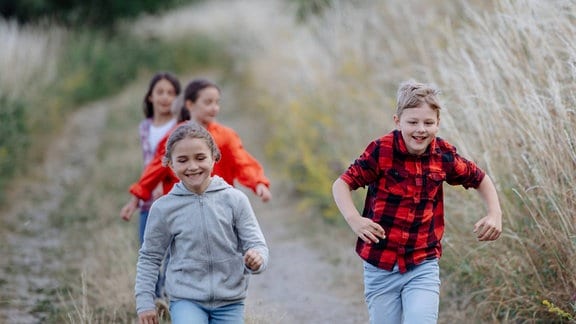 Kinder haben Spaß und rennen den Feldweg entlang.