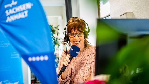 Moderatorin Sabine Küster lächelt und hält Mikrofon in der Hand