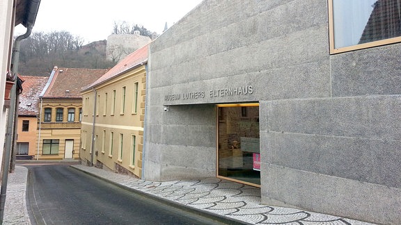 Blick auf das Museum "Luthers Elternhaus", ein hellgrauer, flacher Neubau schließ an ein älteres Gebäude an. 