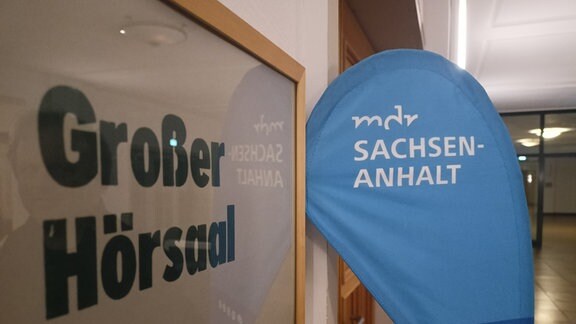 Ein Türschild "Hörsaal", daneben ein Logo von MDR SACHSEN-ANHALT
