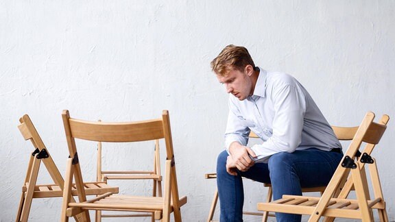 Ein Mann sitzt im Stuhlkreis.