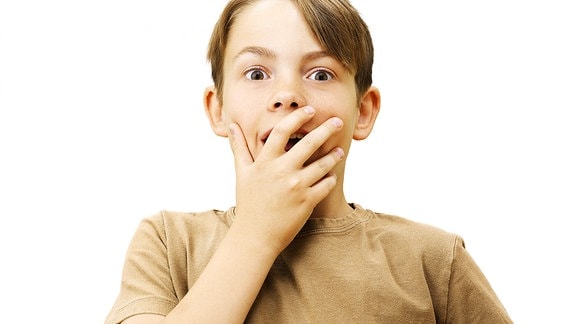 Symbolbild: Ein Junge hält sich eine Hand vor dem Mund.