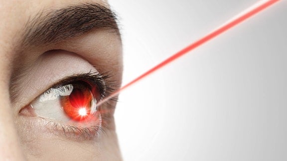 Nahaufnahme eines weiblichen Auges mit einem auf die Iris gerichteten Laserstrahl.