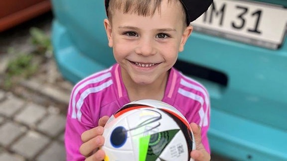Ein kleiner Junge hält einen Fußball.