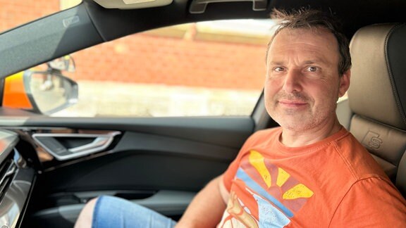 Ein Mann in einem orangen T-Shirt sitzt in einem Fahrschulauto auf dem Beifahrersitz: Es ist Fahrlehrer Yves Klinkhardt aus Erfurt