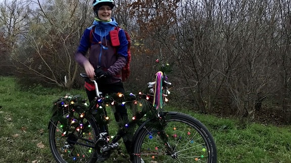 Ein Fahrrad ist mit Zweigen und Lichterketten geschmückt.