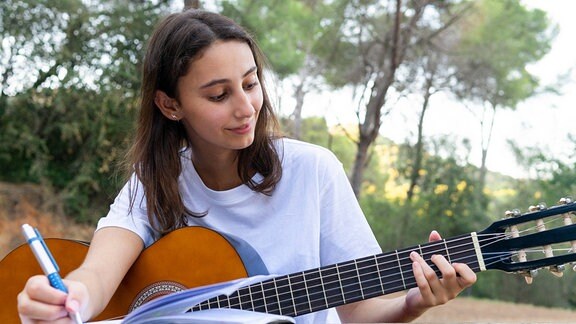 Ein weiblicher Teenager mit klassischer Gitarre.