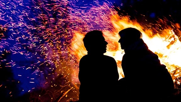 Ein Paar sitzt vor einem brennenden Maifeuer.