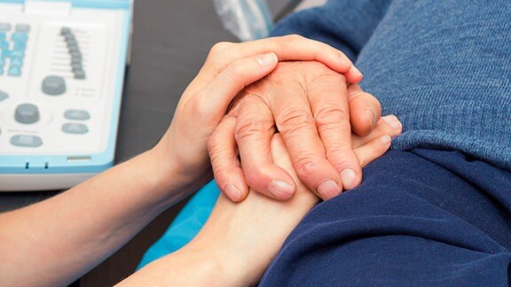 Krankenschwester hält Hand eines Patienten