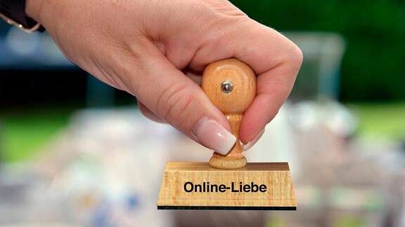 Frauenhand mit Stempel mit der Aufschrift Online-Liebe