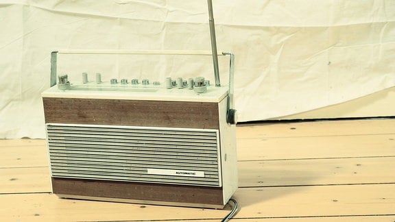 Ein älteres Radiogerät steht auf einem Holzfußboden.