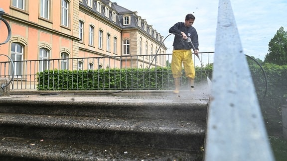 Ein Arbeiter reinigt mit einem Dampfstrahler die Treppen zum Neuen Schloss