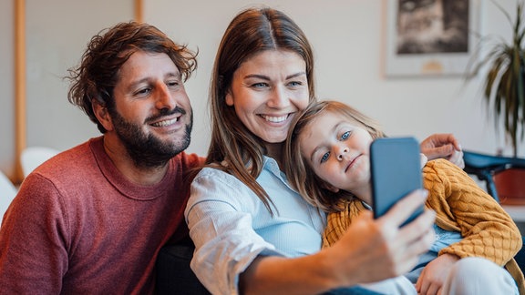 Frau macht Selfie von ihrer lächelnden Familie.