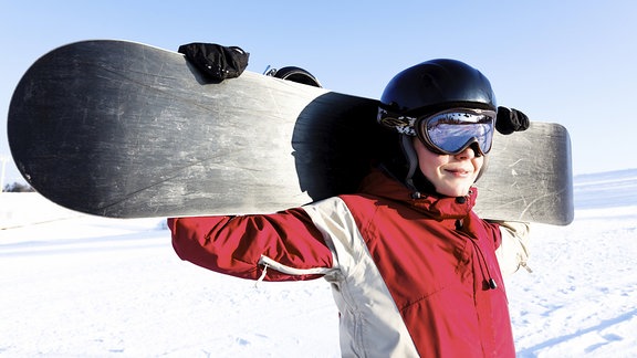 Frau mit Snowboard auf den Schultern