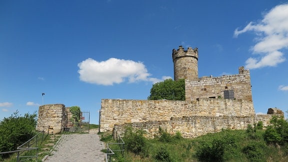 Die Rest einer mittelalterlichen Burg aus grobem Stein ragen in den blauen Himmel 