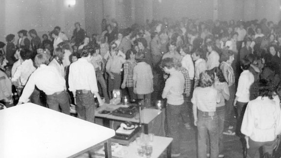 Gruppe von Menschen bei einer Tanzveranstaltung im Zentrum der Jugend Mühlhausen zu DDR-Zeiten. Die Menschen stehen dicht gedrängt und tanzen. Es ist ein historisches Foto aus DDR-Zeiten.