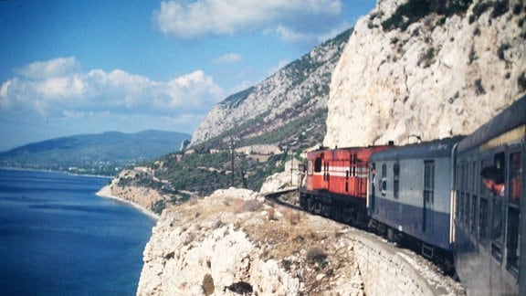 Ein Zug fährt an einer Steilküste entlang.