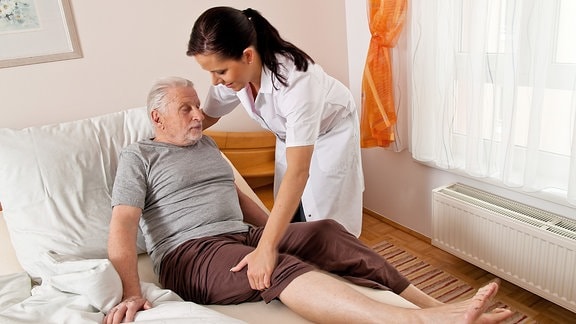 Eine Pflegerin betreut einen älteren Mann