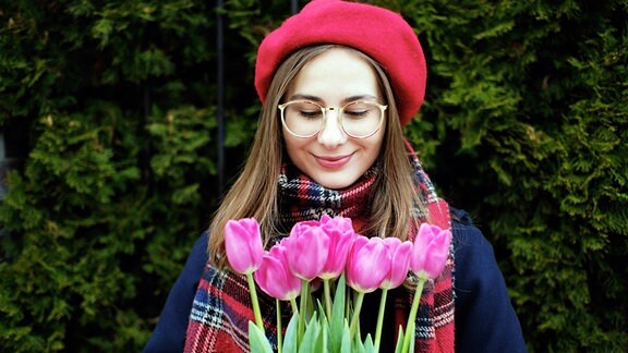 Eine junge Frau freut sich über einen Strauß Blumen