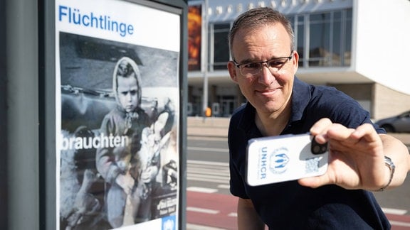Chris Melzer, Pressesprecher UNHCR, vor dem Motiv eines Fluechtlingskindes von 1945