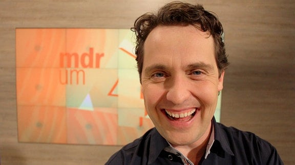 Stefan Ganß lacht im MDR um 4-Studio in die Kamera
