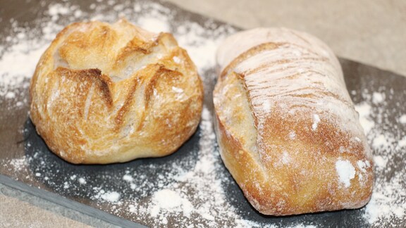 Frisch gebackene Brötchen liegen auf einem Brett.