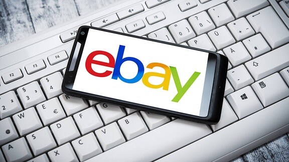 Ein Smartphone mit ebay-Logo auf einer Computertastatur