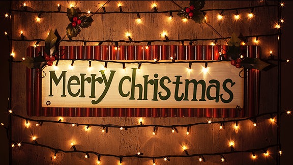 "Merry Christmas" steht auf einem von einer Lichterkette umgebenen Schild