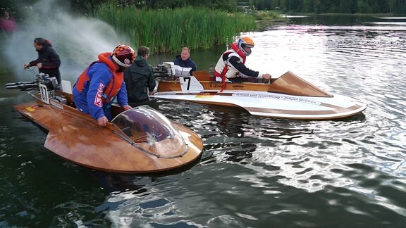 Eine Gruppe Menschen macht zwei Rennboote startklar.